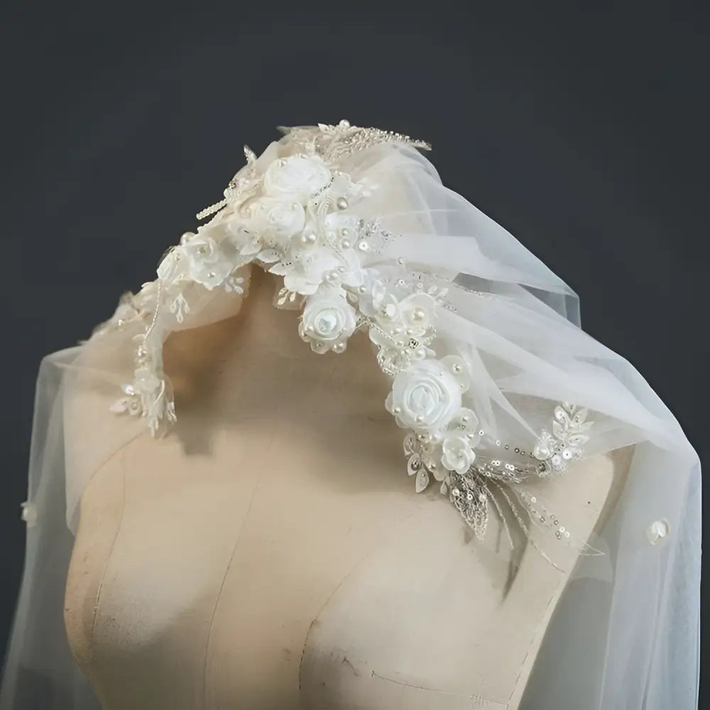 A delicate white bridal veil with vintage beaded lace and embroidered roses in a lace petal headdress design
