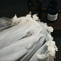 A delicate white bridal veil with vintage beaded lace and lace petal headdress featuring embroidered floral appliqués
