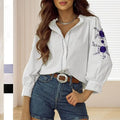 White blouse with vintage floral embroidered purple flowers on the sleeve and lace trim at the cuffs