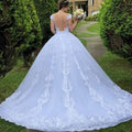 Back view of a vintage lace white wedding dress with an open back and floral train featuring intricate embroidery on main fabric