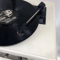 Black vinyl record with jf1 logo on white label resting on cream vintage white gramophone for classical living room stereo
