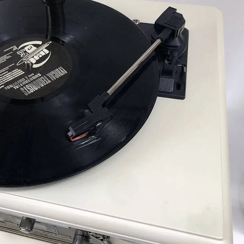 Black vinyl record with jf1 logo on white label resting on cream vintage white gramophone for classical living room stereo