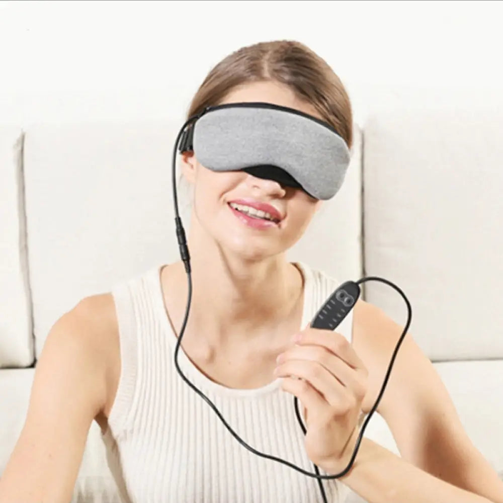 Visionary smart eye massager mask in gray fabric with black adjustable straps and matching remote control for relaxation