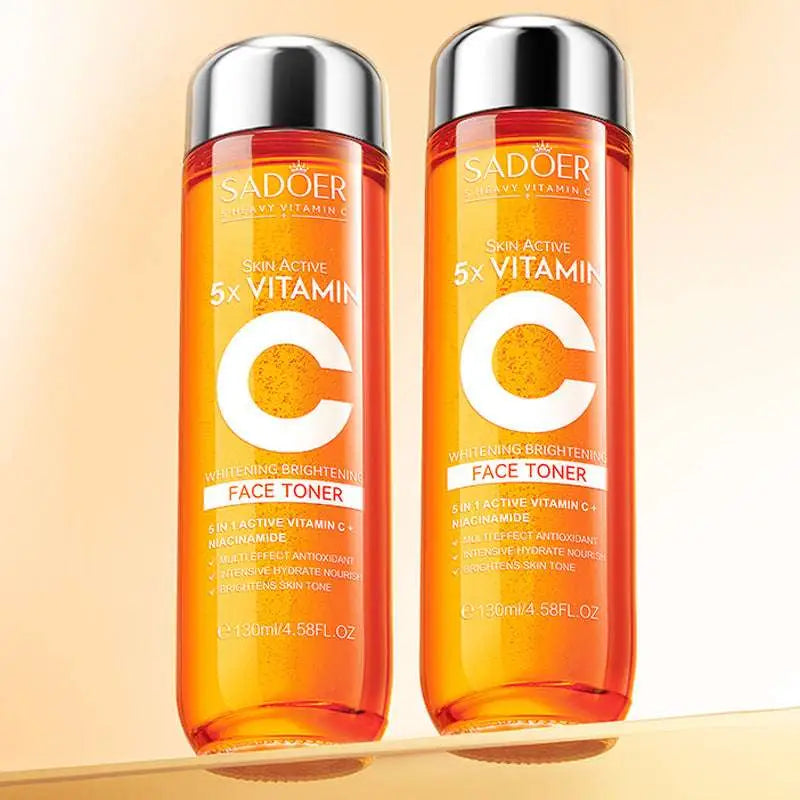 Two transparent orange vitamin c whitening face toner bottles with silver caps in an orange rectangular box gift set