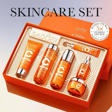 Orange rectangular box containing a vitamin c whitening skin care gift set with five distinct product bottles and metallic accents