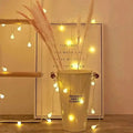Cream-colored cylindrical bucket with original sweet flower text and red handles containing warm yellow sunshine pearl lights led pearls