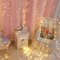 Warm yellow sunshine pearl lights with led pearls draped across a pink curtain and chair creating cozy ambiance