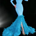 A turquoise mermaid gown with fitted bodice, long sleeves, sparkling embellishments, and a feather trailing hip train