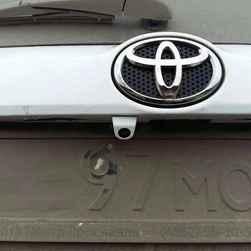 Silver toyota emblem with black perforated center on white vehicle front grille for waterproof car camera night vision reversing system