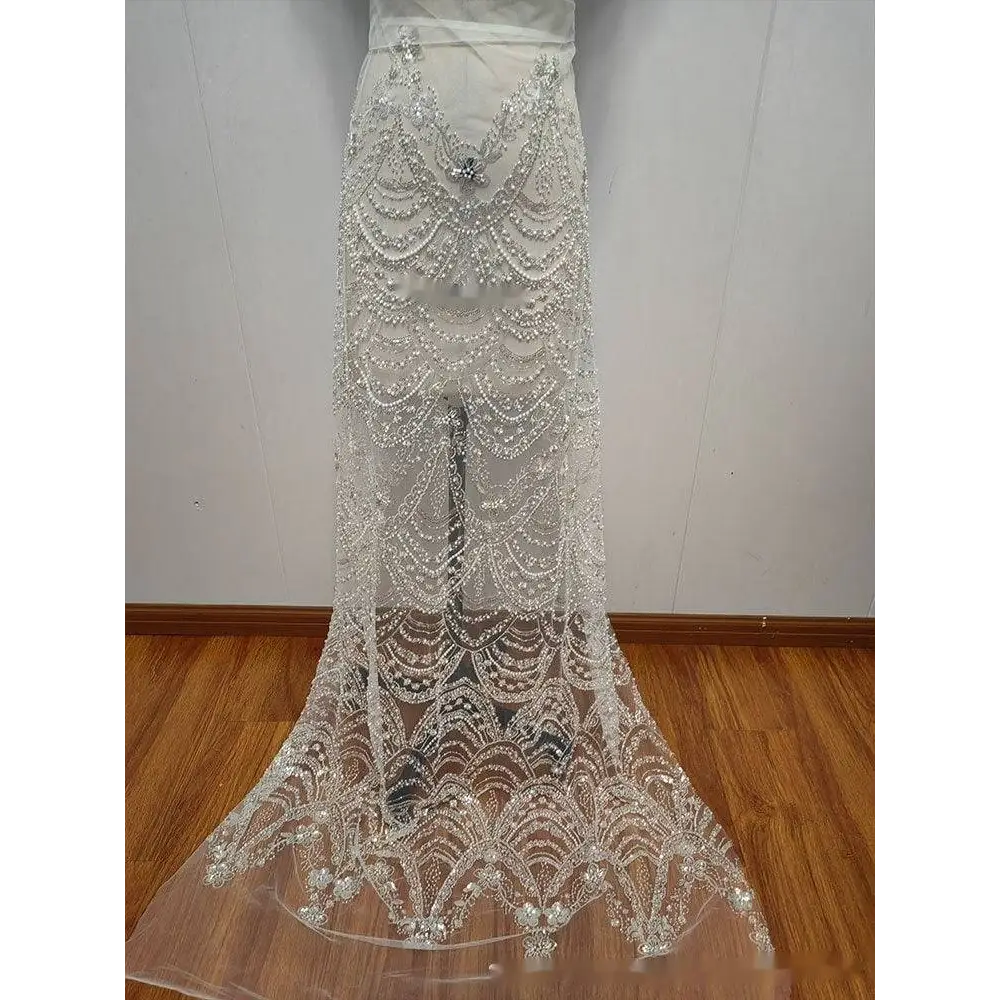 A sheer white lace wedding skirt with intricate silver wave style sequin bead lace in a cascading scalloped design