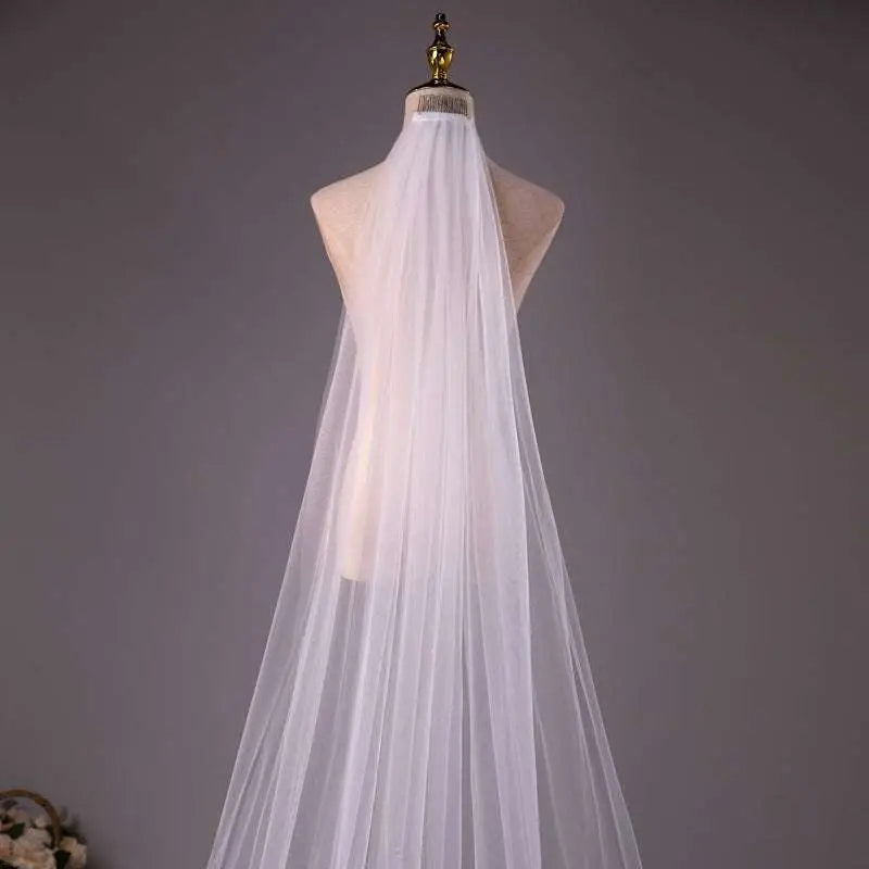 A delicate white tulle wedding bride double-layer trimming veil with comb elegantly draped on a mannequin
