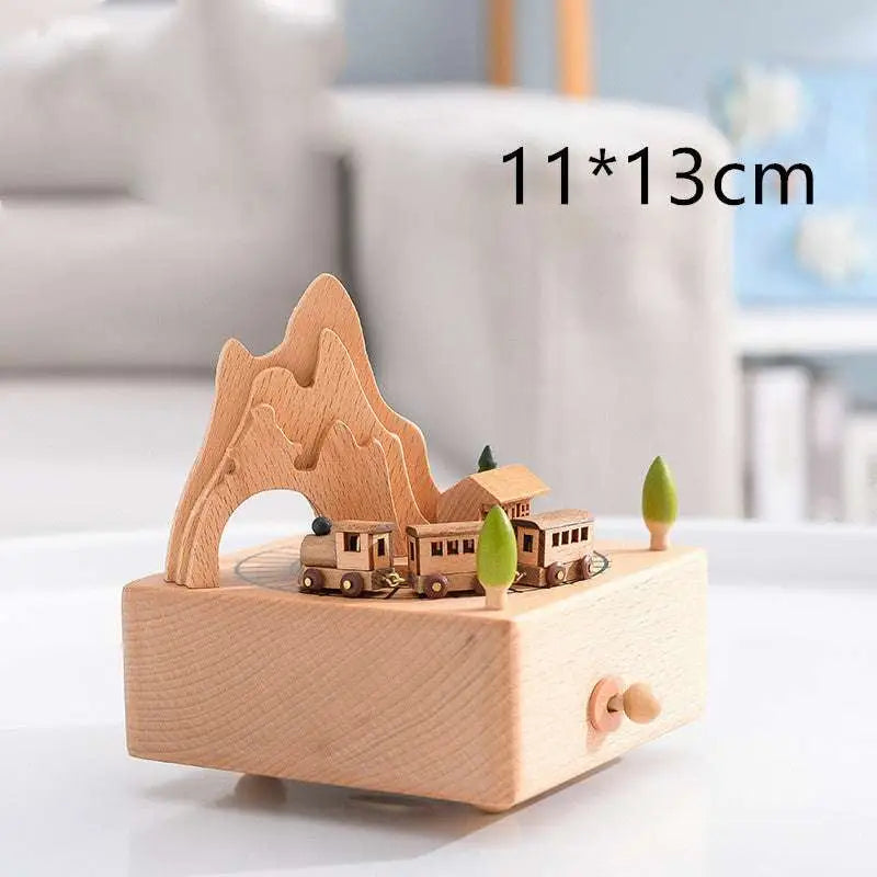 A light wood-colored wooden rotating music box with a miniature train and mountain scene for wedding rocking horse table decoration