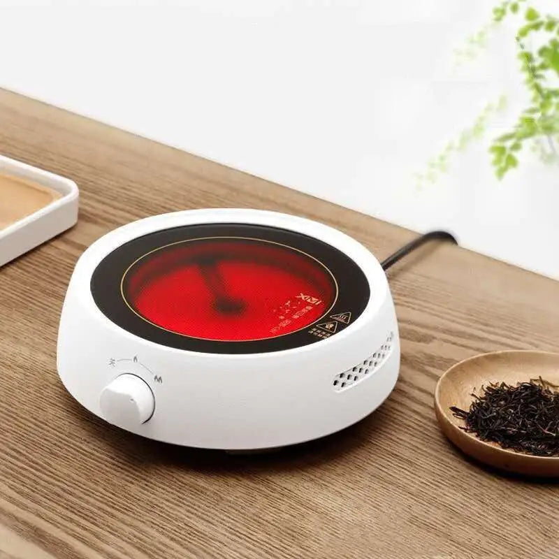 White ceramic electric earthenware oven with glowing red heating plate and black control dial for efficient cooking