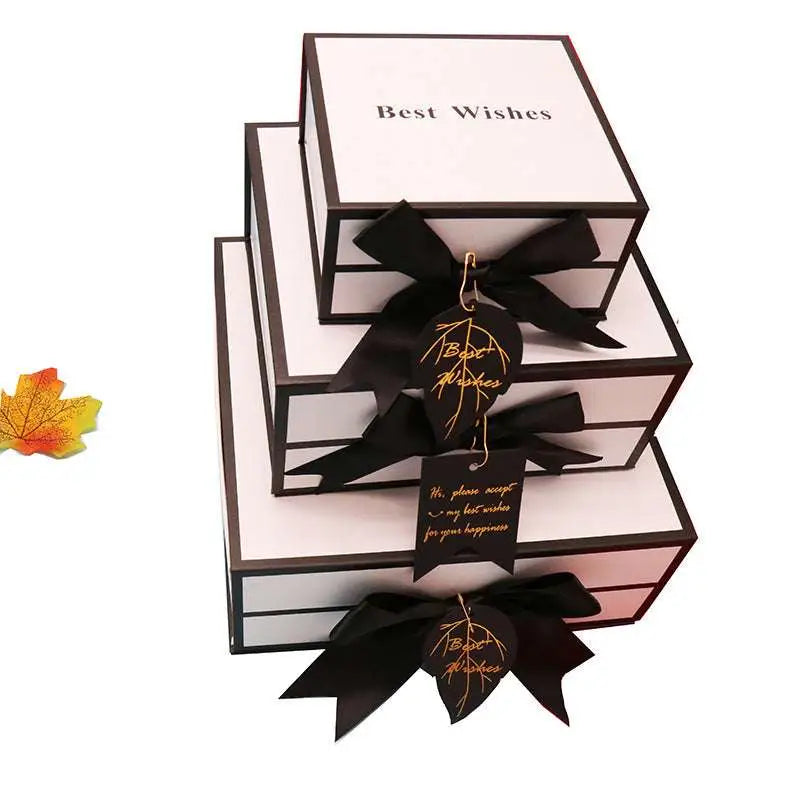Stacked white clamshell gift boxes with black satin bow and best wishes tag ideal for box lipstick packaging