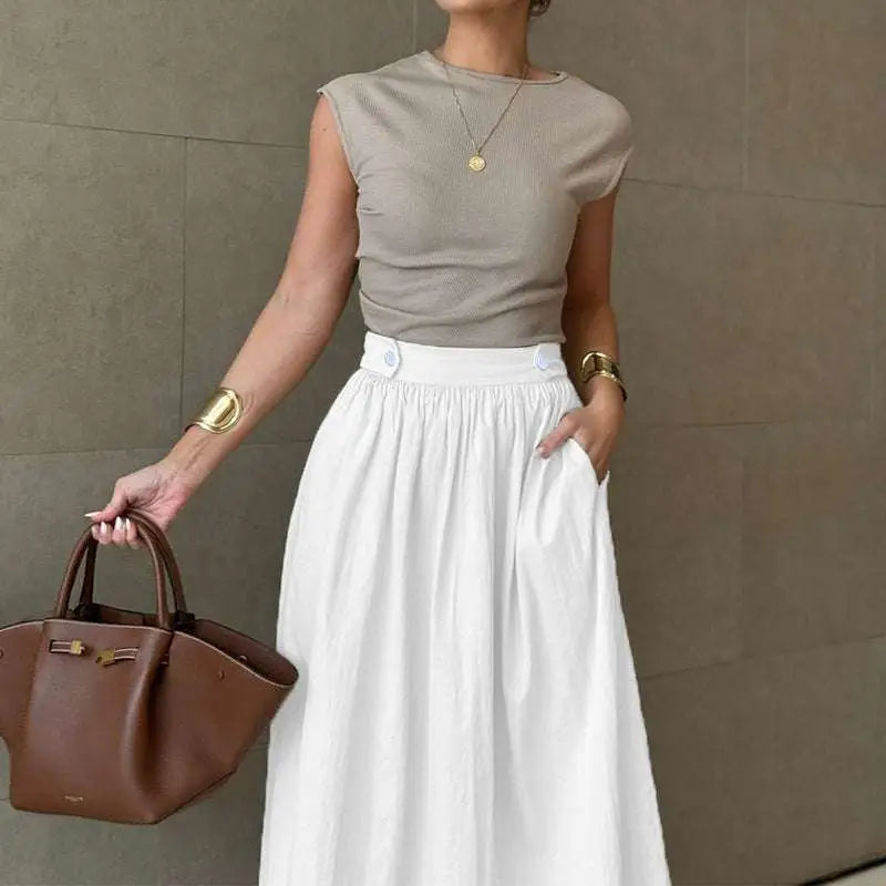 Brown leather handbag with gold-tone hardware and top handles paired with slimming large hem white cotton linen midi skirt