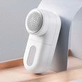 White electric lint and bulb remover with perforated circular head and smooth plastic body for luxury women’s fashion care