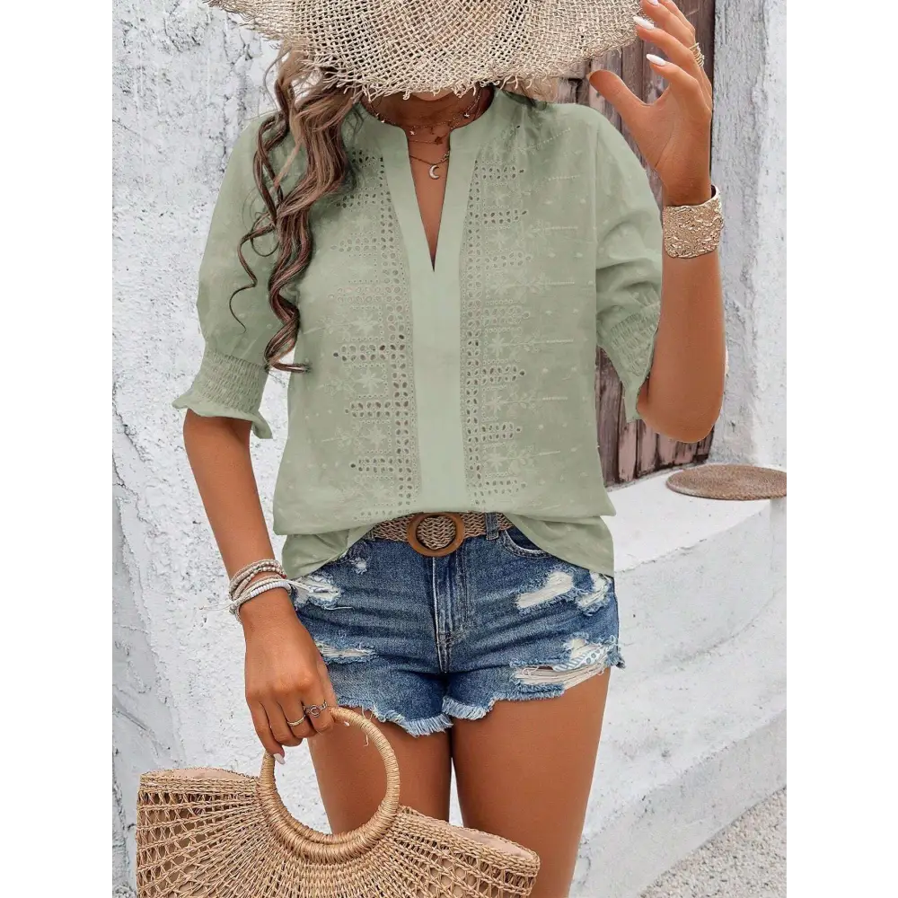 Light green short-sleeved blouse with delicate white eyelet embroidery and v-neckline featuring puff sleeve design