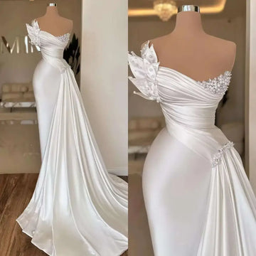 A white graceful satin off-the-shoulder wedding dress with beaded embellishments and a flowing train