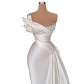 Elegant white graceful satin off-the-shoulder wedding dress with one-shoulder design, beaded embellishments, and fabric flowers