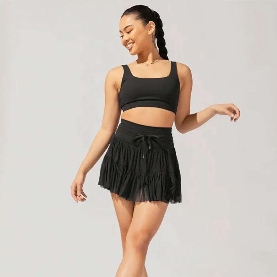 Black ruffled mini skirt with tied waistband paired with white high waist pleated skirt and safety pants summer use