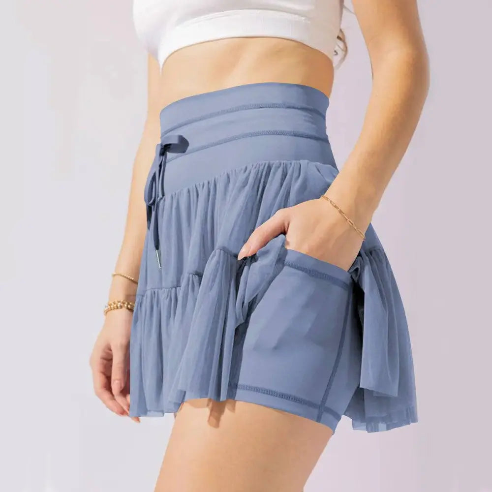 Light blue tiered athletic shorts with drawstring waistband and side pockets paired with white waist pleated skirt safety pants summer