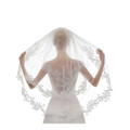 A delicate white ivory lace bridal veil with intricate ivory embroidery applique floral edges draped on bride