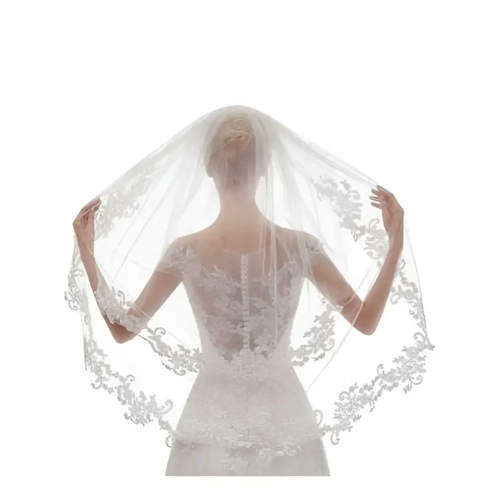 A delicate white ivory lace bridal veil with intricate ivory embroidery applique floral edges draped on bride