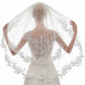 A delicate white ivory embroidery applique floral bridal veil with intricate lace edges worn by a bride