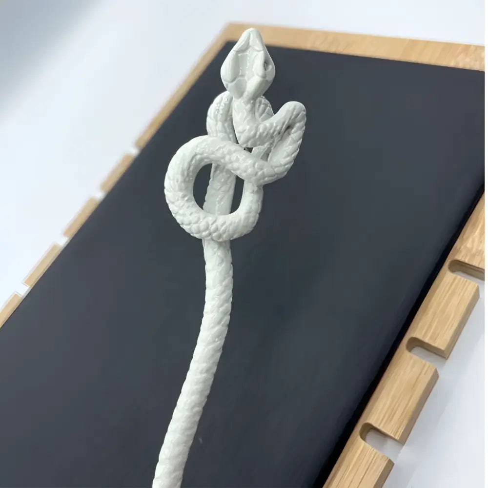 White knotted rope retro style hairpin featuring a white ceramic intricately coiled snake with textured scales