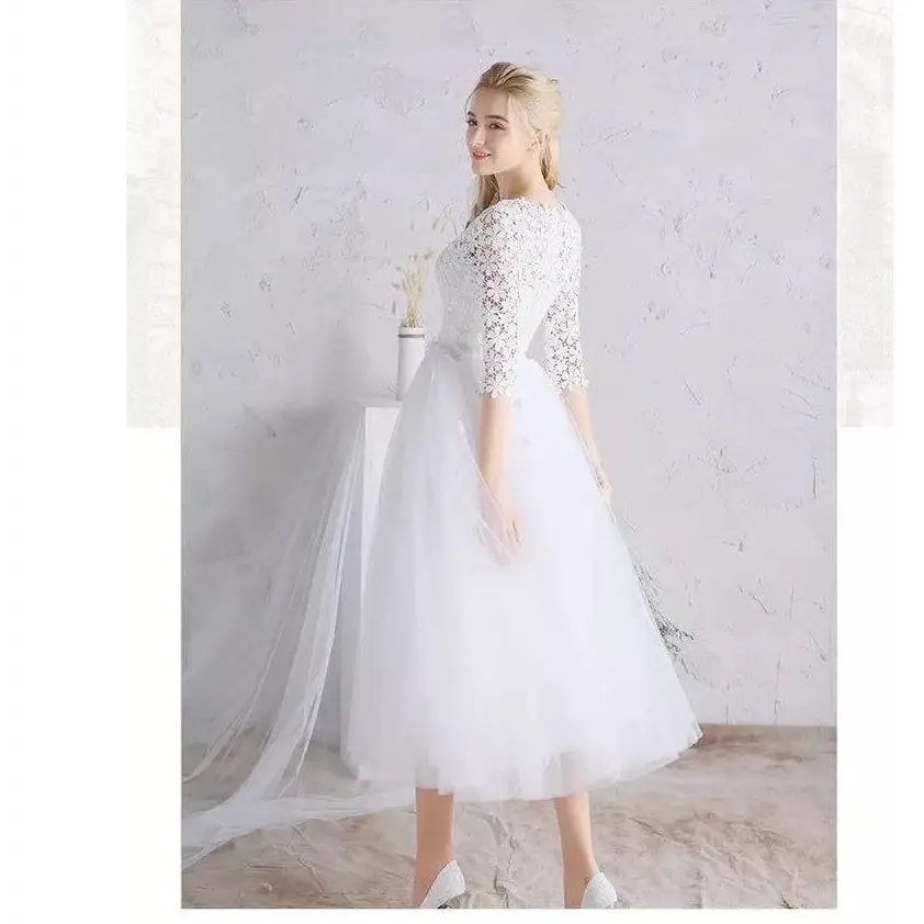 White lace floral wedding dress with three-quarter sleeves, fitted embroidered bodice, and flowing tulle skirt with train
