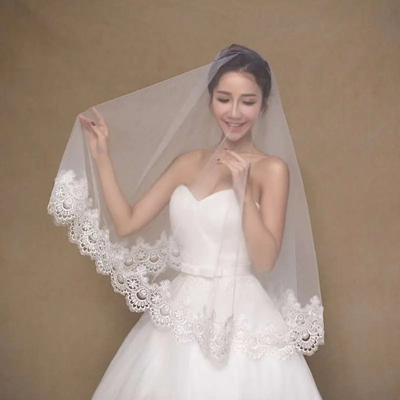 A delicate white lace bride veil with intricate white lace floral patterns along the edges for bridal wear
