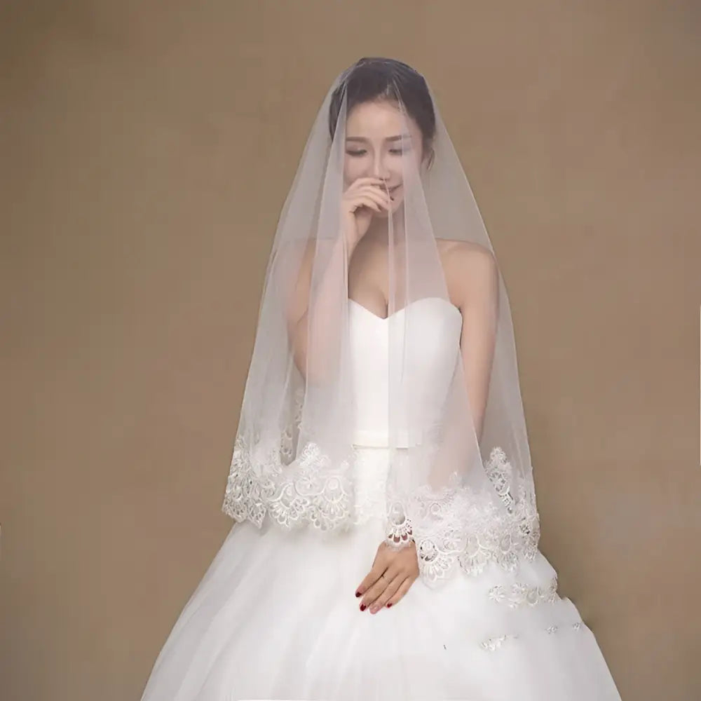 Delicate white lace bride veil with white lace floral embroidery and sheer flowing design for bridal wear
