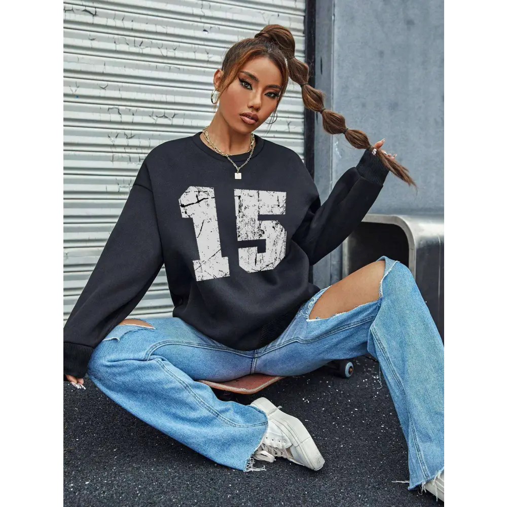 Black distressed graphic crew neck sweatshirt with white number 15 print and ribbed knit cuffs and hem