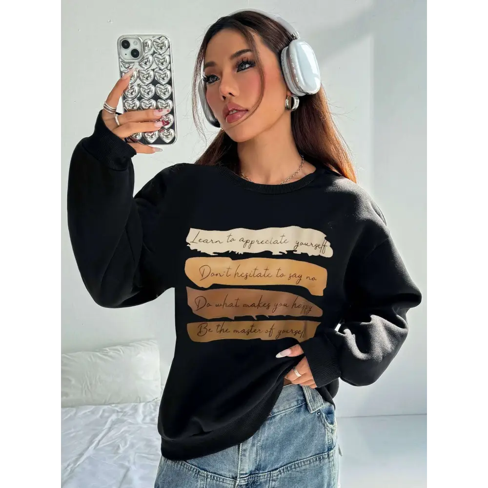 Black oversized long sleeve sweatshirt with motivational quote printed in beige and tan horizontal stripes