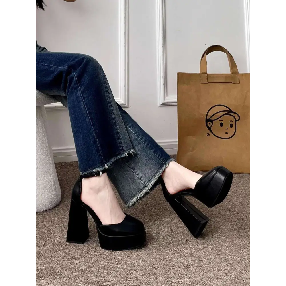 Black platform mary janes with a chunky block heel and ankle strap complement the white patent super high heel platform design