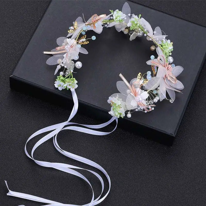 White pearl and gold children’s wreath adorned with sheer fabric flowers, gold butterflies, pearl beads, and flowing ribbon tail