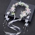 Delicate white and light pink children’s wreath adorned with pearls, gold accents, butterflies, and flowing satin ribbons