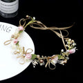 Delicate children’s wreath adorned with pink and white fabric flowers, gold stems, pearls, crystals, and beige satin ribbons