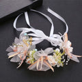 Delicate white children’s wreath adorned with pearl accents, sheer tulle petals, and a gold butterfly charm headband