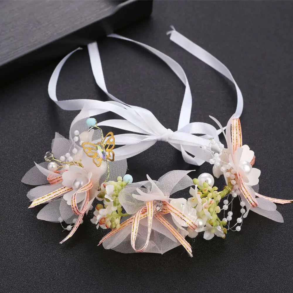 Delicate white children’s wreath adorned with pearl accents, sheer tulle petals, and a gold butterfly charm headband