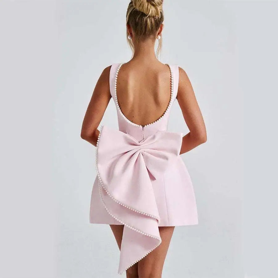 A sleek white satin backless dress summer with pearl embellished neckline and asymmetrical bow flared skirt