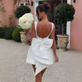 White satin backless dress summer with pearl embellished detailing, deep back cutout, and layered bow at the waist