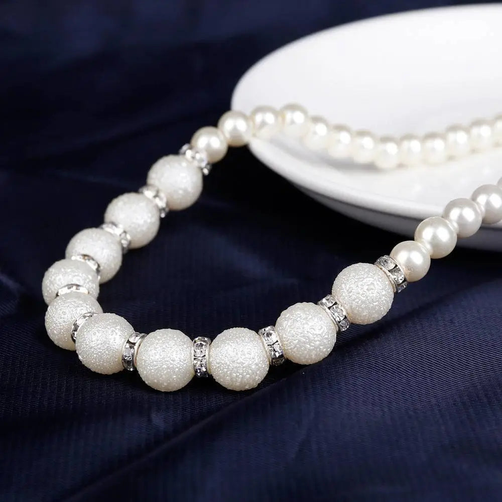 Elegant white pearl wedding necklace with smooth and textured beads and silver-toned spacer charms for bridal wear