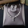 Silver white rhinestone necklace earrings set with floral design and clear crystal accents on dark gray velvet stand