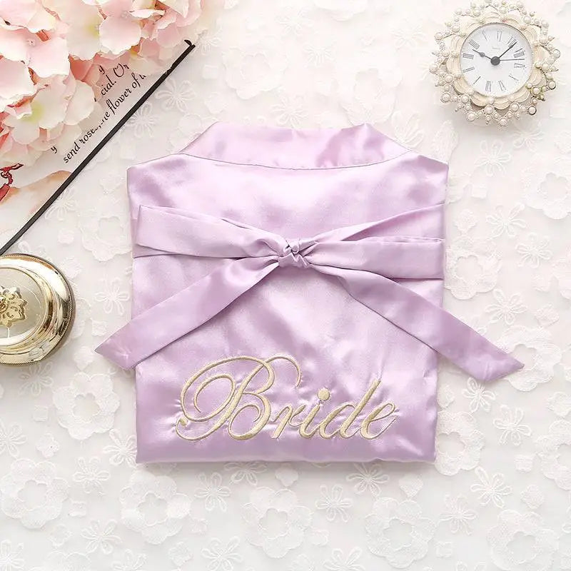 Lavender satin bridal pajamas simulation featuring gold embroidered bride lettering and matching waist ribbon bow