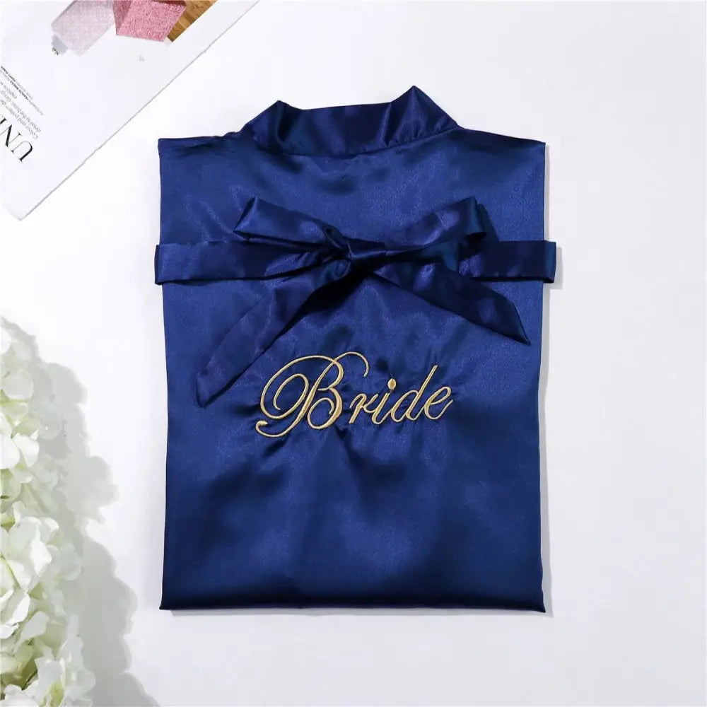 Navy blue satin bridal pajamas simulation with gold embroidered lettering and matching ribbon bow for elegant nightwear