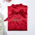 A vibrant red satin bridal pajamas simulation with gold embroidered bride script and matching waist ribbon bow