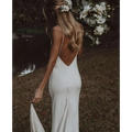 Back view of a white satin evening gown with delicate spaghetti straps and a flowing train brigade cutout design