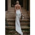 White satin evening gown with flowing train brigade and delicate spaghetti straps shown from the back side with deep cutout