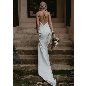 White satin evening gown with flowing train brigade and delicate spaghetti straps shown from the back side with deep cutout